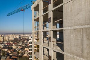 Aerial view of concrete frame of tall apartment building under c