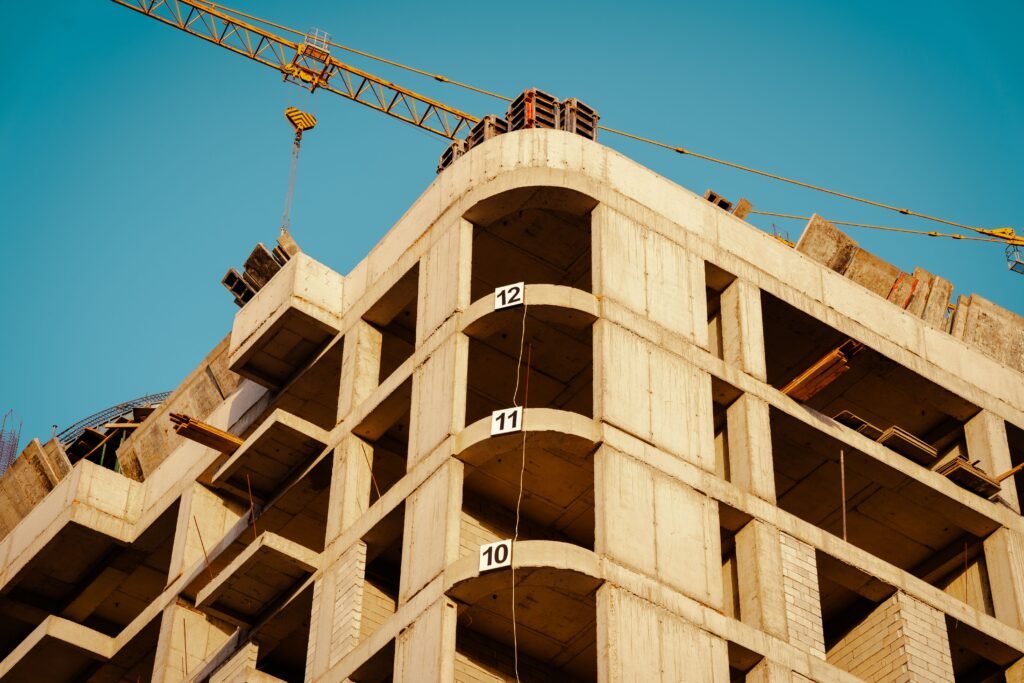 Statybvietė aukštybinio pastato po aiškiu mėlynu dangumi su kranu fone